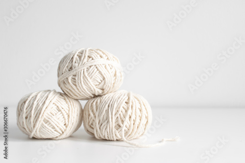 Balls of white yarn on a white wall background. Threads of wool boho image. Space for text. Good for macrame and handicrafts banners and advertisement