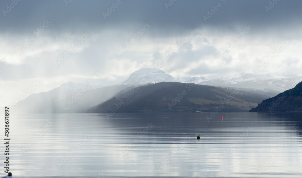 A view across Loch Ness looking down the length of the lake, with dark clouds above, in Scotland, UK