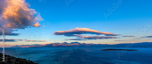 Cretan seascape at sunset with mountains, moon and clouds. Crete, Greece.