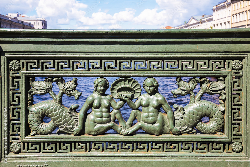 Cast iron railing with images of mermaids on the Anichkov bridge over the Moika river, St. Petersburg, Russia