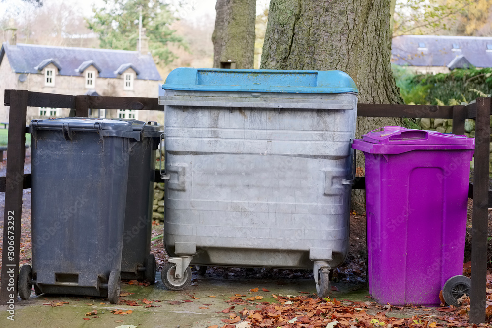 Steel container with black and purple wheelie bin outside house UK Steel container with black and purple wheelie bin outside house UK
