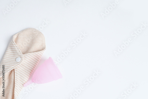 reusable pad and pink menstrual cup on white background. woman period concept. eco friendly flat lay.