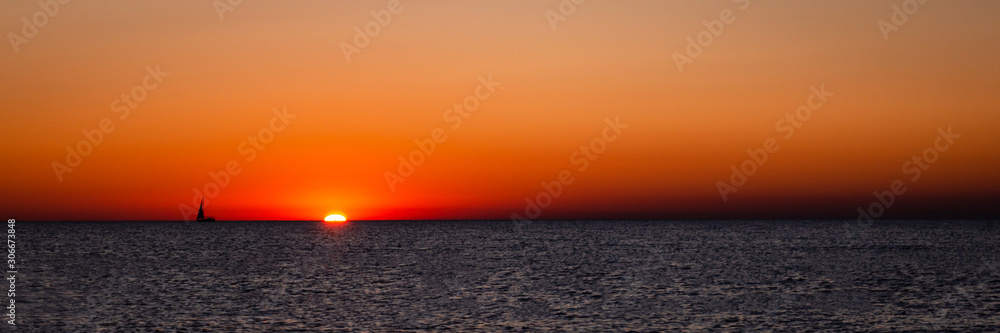 Fototapeta premium Dramatic sunset with sailboat silhouette