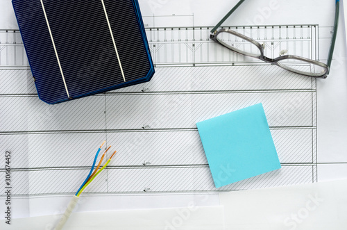 Solar cell, eyeglasses, post it and cable in  a conceptual image for thinking of swithching to solar power. Top view over blueprints with copy space. photo