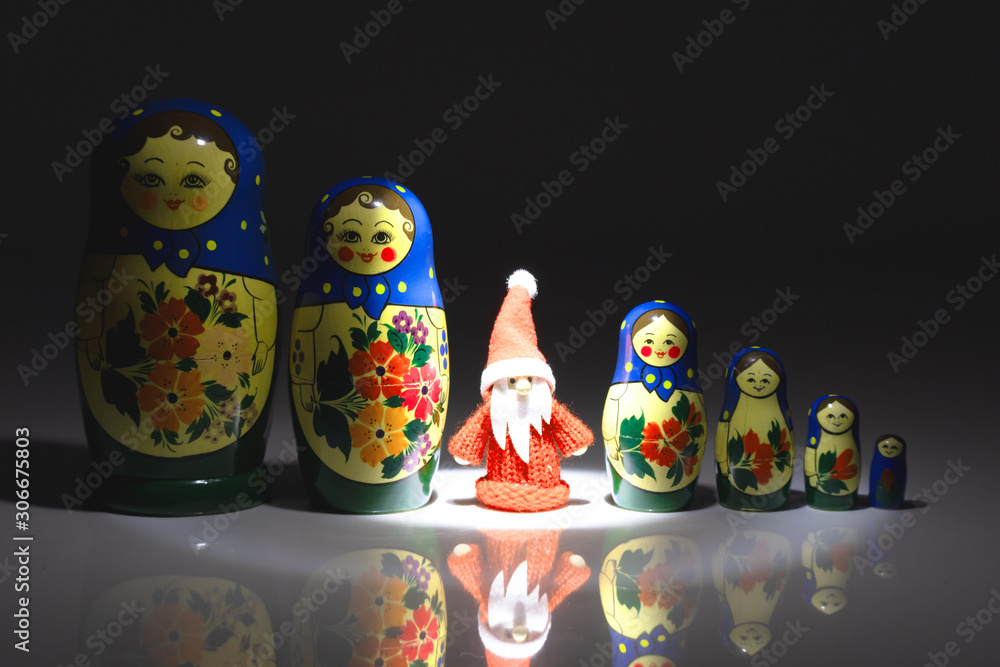Weihnachtsmann im Rampenlicht zwischen einer Reihe von Matroschka-Puppen Weihnachtsmann im Rampenlicht zwischen einer Reihe von Matroschka-Puppen