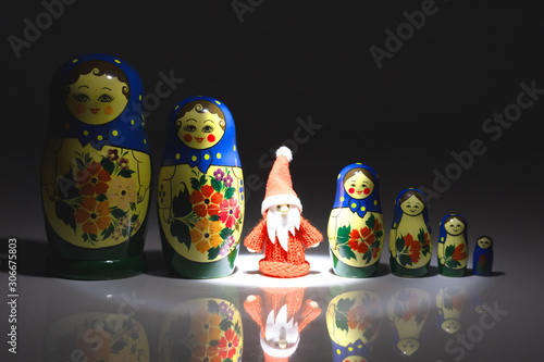 Weihnachtsmann im Rampenlicht zwischen einer Reihe von Matroschka-Puppen