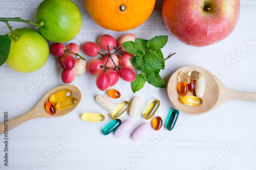 Multivitamin supplements from fruit on white wooden background