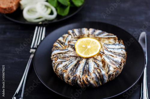 Pilaf with hamsi anchovy fish. Traditional Turkish food - Kapama Pilav - on black wooden table.