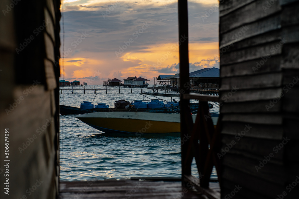 Silhouette of boats and unidentified man working early morning during sunrise in Semporna, Sabah, Malaysia.