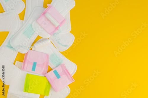 Top view of packed and unpacked many feminine pads with copy space on a yellow background. Flat lay mockup with space for text