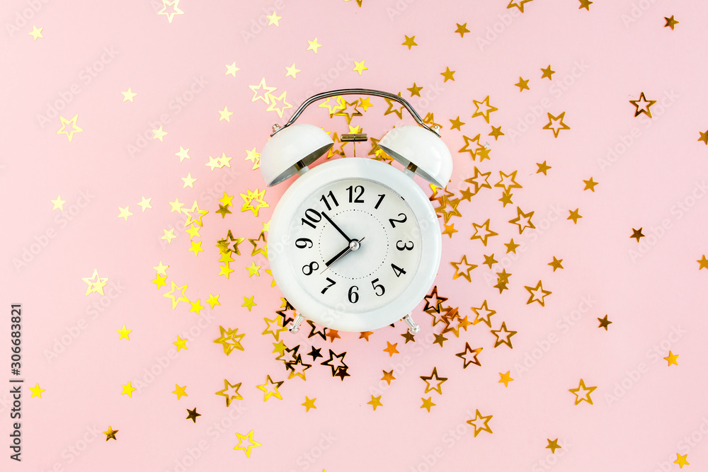 Round frame, alarm clock covered golden stars confetti, glitter decoration on a pink, festive background. Christmas or New Year pattern. Flat lay, top view Round frame, alarm clock covered golden stars confetti, glitter decoration on a pink, festive background. Christmas or New Year pattern. Flat lay, top view