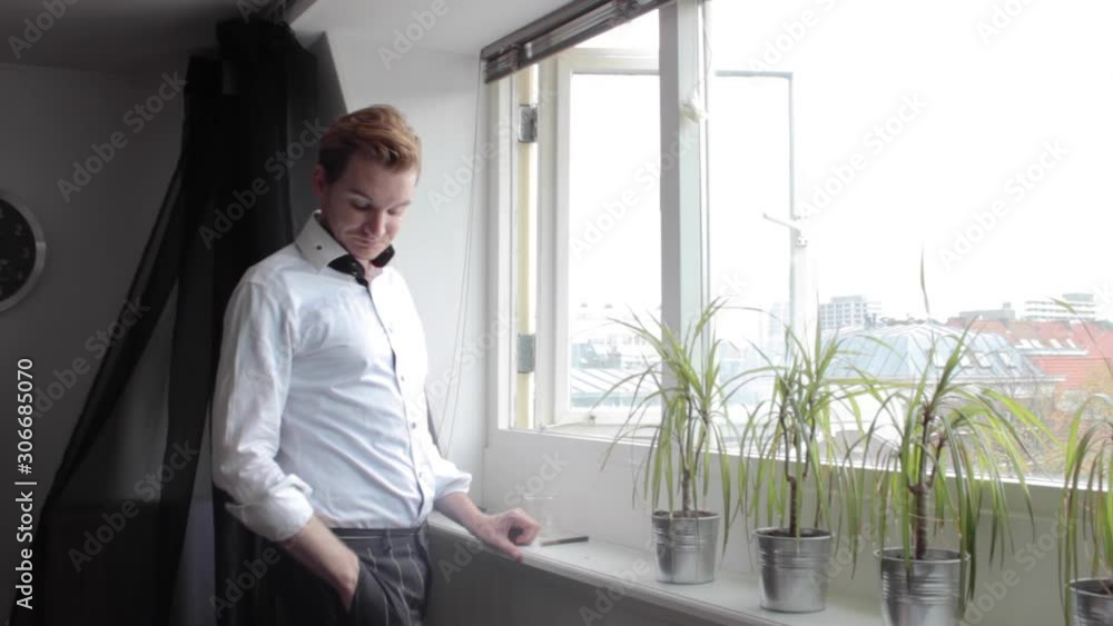 Man wearing suit looks at window and receives text message on phone Man wearing suit looks at window and receives text message on phone