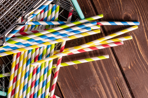 Lot of whole paper straw in shopping basket flatlay on brown wood