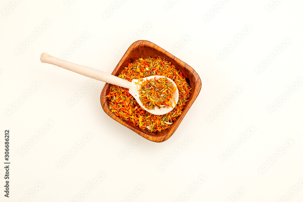 Dried calendula and wooden spoon on a light background. Apothecary herbs. Minimalist style Dried calendula and wooden spoon on a light background. Apothecary herbs. Minimalist style