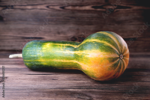Yellow-green oblong shaped pumpkin, natural wooden background, diet food, Halloween