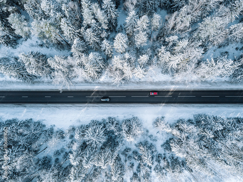 Aerial view of winter road and forest with snow covered trees in Finland
