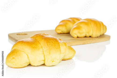 Group of three whole sweet golden mini croissant on bamboo cutting board isolated on white background