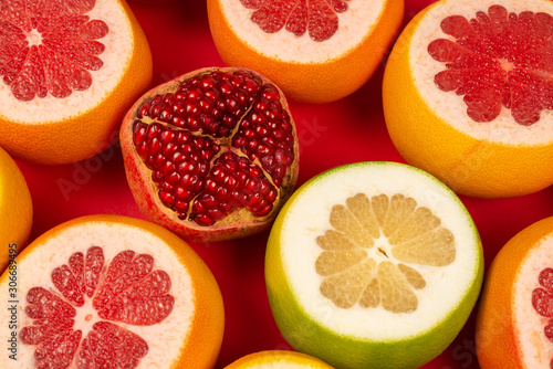 Grapefruit, orange, pomegranate, citrus sweetie on red background.