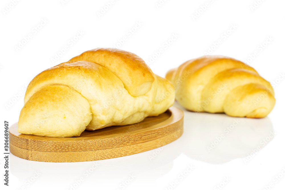 Group of two whole sweet golden mini croissant on bamboo coaster isolated on white background