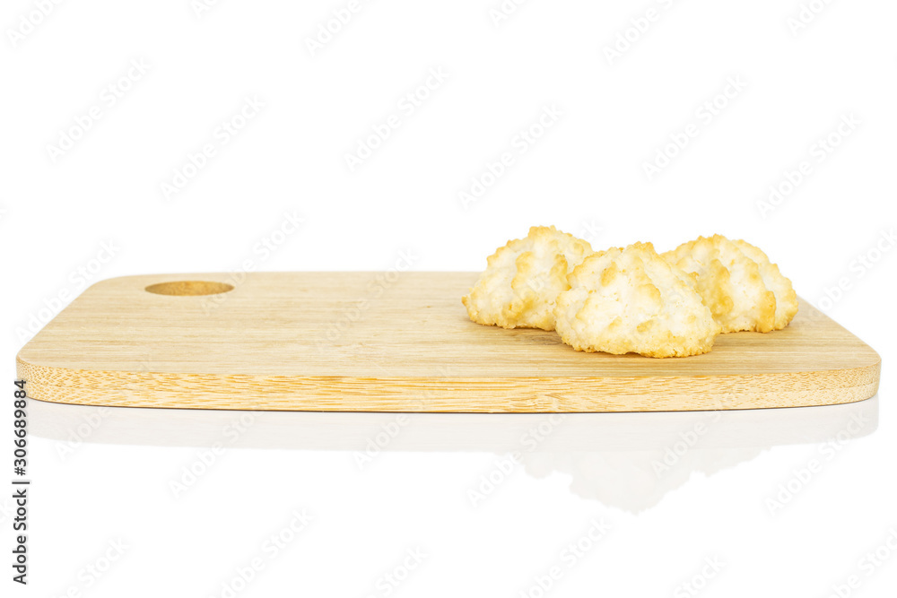 Group of three whole homemade golden coconut biscuit on bamboo cutting board isolated on white background