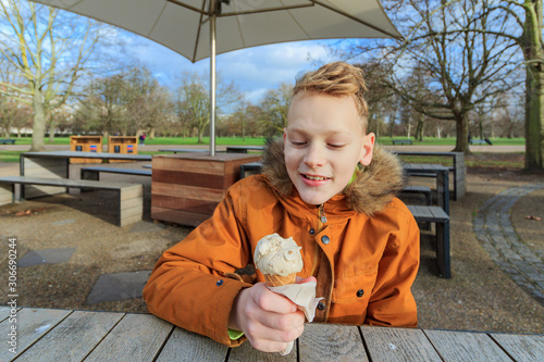 Blond boy eating ice cream at the table cafe near playground with pirate ship, in Royal Borough of Kensington and Chelsea, London. Diana, Princess of Wales in Kensington Gardens. Broad Walk Cafe photo