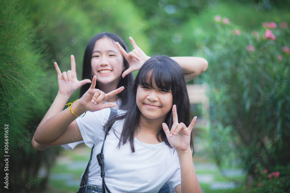 portrait of two asian teenager relaxing with happiness in green park portrait of two asian teenager relaxing with happiness in green park