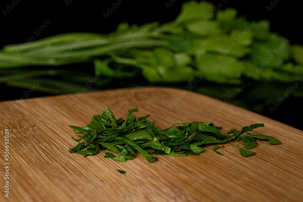 Lot of whole lot of pieces of fresh green parsley on bamboo cutting board isolated on black glass Lot of whole lot of pieces of fresh green parsley on bamboo cutting board isolated on black glass