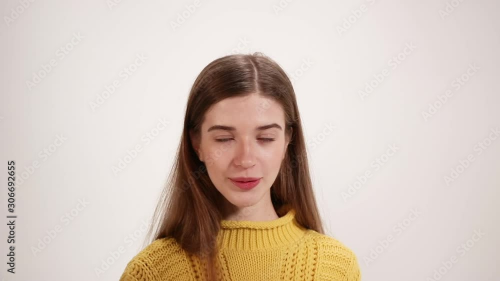 Girl in a yellow sweater straightens her hair and smiles white background Girl in a yellow sweater straightens her hair and smiles white background