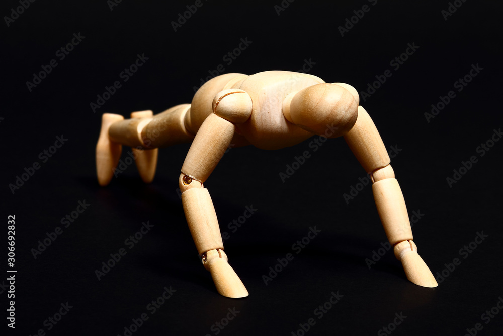 Conceptual image of a wooden manikin doing push ups isolated on a black background Conceptual image of a wooden manikin doing push ups isolated on a black background