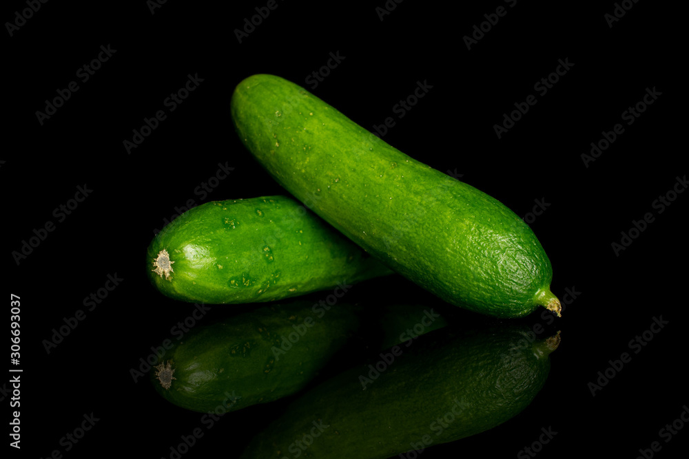 Group of two whole fresh green baby cucumber isolated on black glass Group of two whole fresh green baby cucumber isolated on black glass