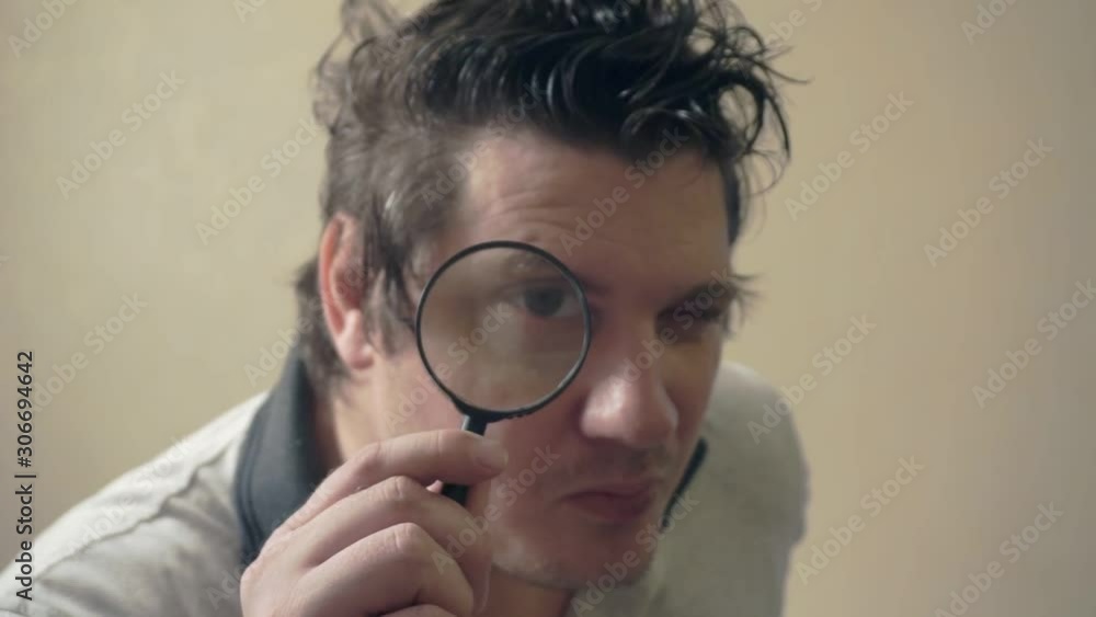portrait of a funny surprised man who is looking at the camera through a magnifying glass.humorous video portrait of a curious man portrait of a funny surprised man who is looking at the camera through a magnifying glass.humorous video portrait of a curious man