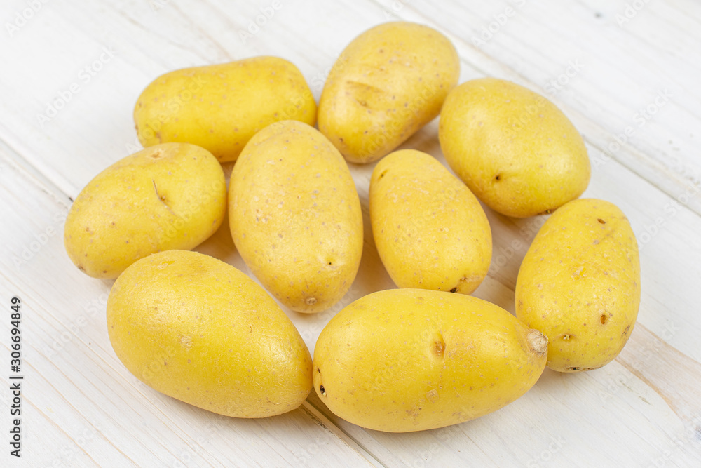 Lot of whole pale yellow potato on white wood