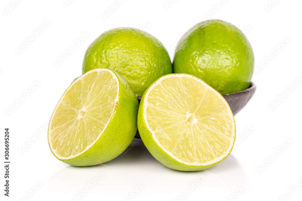 Group of two whole two halves of sour green lime in glazed bowl isolated on white background