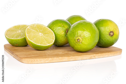 Group of four whole two halves of sour green lime on bamboo cutting board isolated on white background