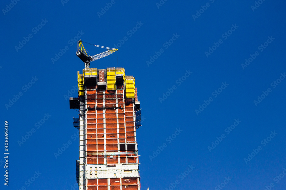 A skyscraper under construction and a blue sky at Harlem, New York City A skyscraper under construction and a blue sky at Harlem, New York City
