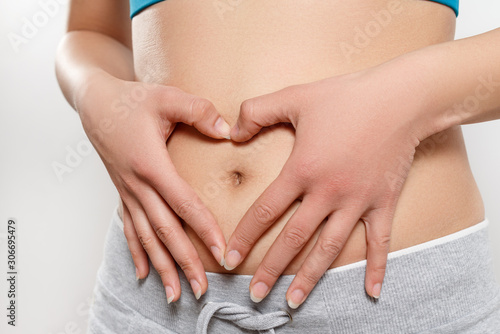 woman shows two hands gesture heart on his stomach. on white. Concept of women's health, early pregnancy