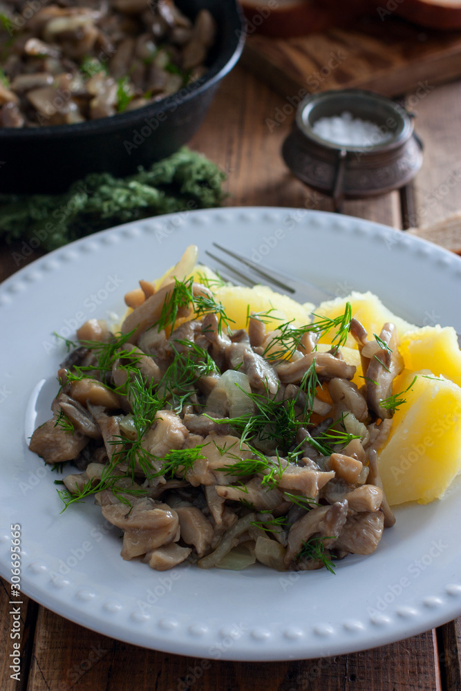 Oyster mushrooms fried with boiled potatoes on a white plate, selective focus Oyster mushrooms fried with boiled potatoes on a white plate, selective focus