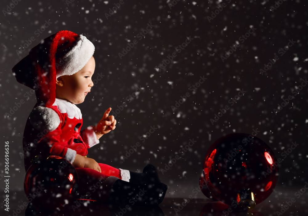 Little toddler boy in santa claus costume and hat rides a wooden horse for children swing with new year gift boxes Little toddler boy in santa claus costume and hat rides a wooden horse for children swing with new year gift boxes