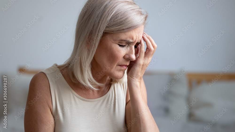 Closeup tired aged woman touches face with hand having migraine Closeup tired aged woman touches face with hand having migraine