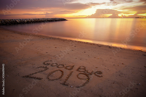 Good Bye 2019 written on the sandy beach during sunset.