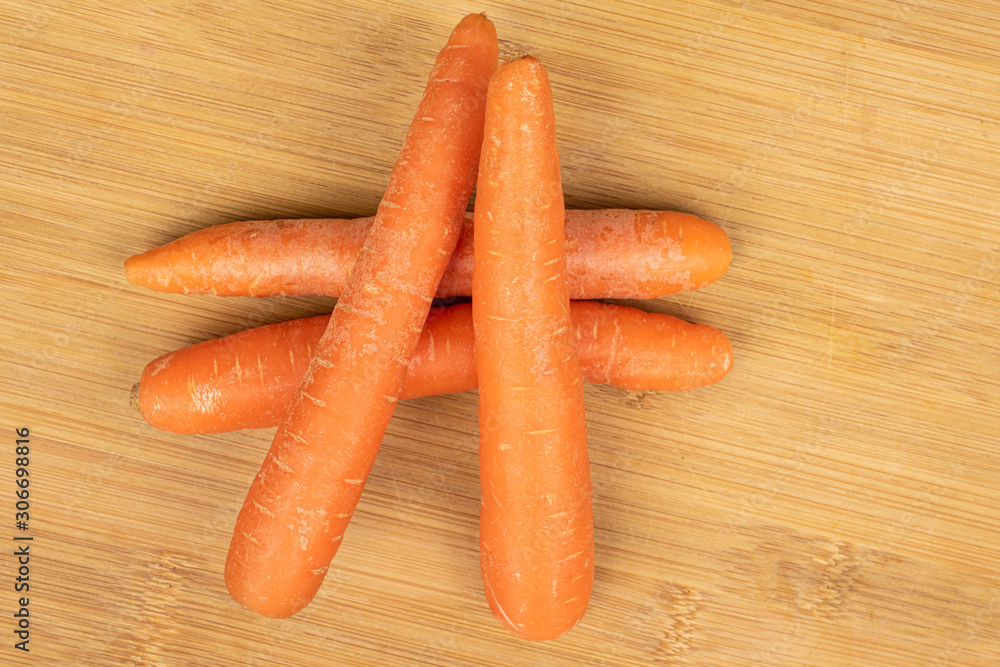 Group of four whole fresh orange carrot flatlay on light wood Group of four whole fresh orange carrot flatlay on light wood