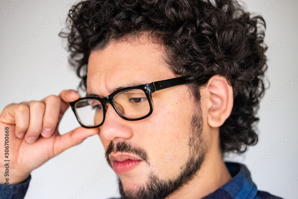 Latin American man with curly hair and glasses, looking upset, worried expression, on a white background  