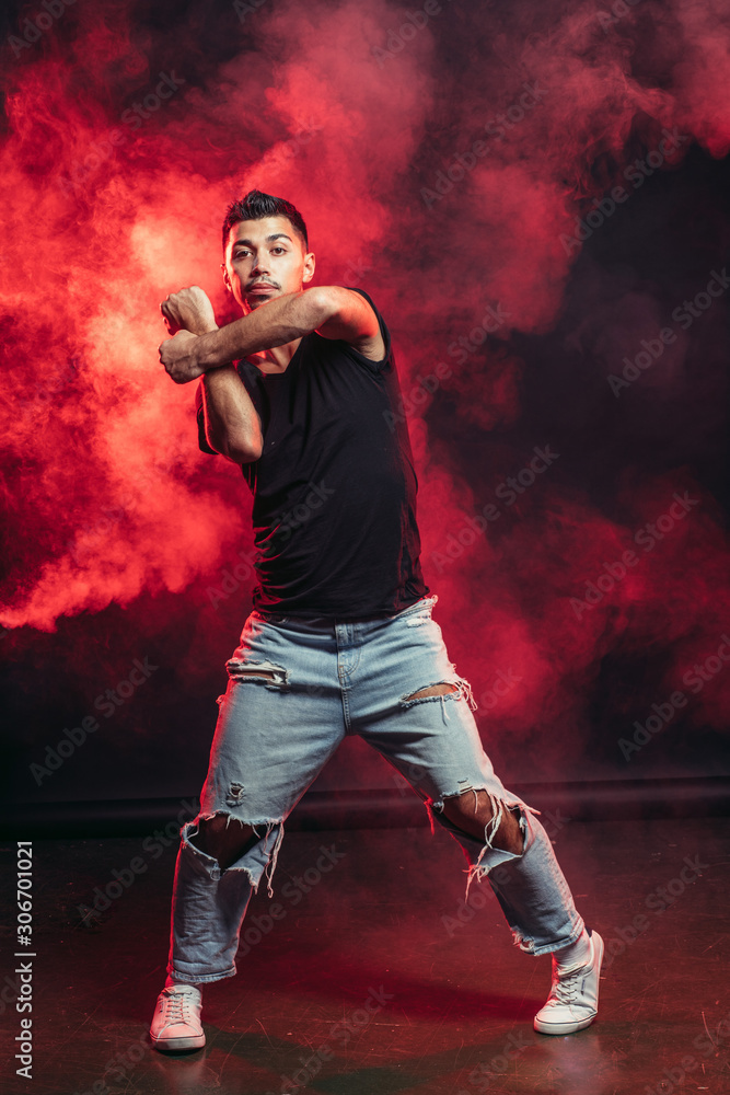 handsome man dancing isolated over smoky background, wearing casual wear, street dance
