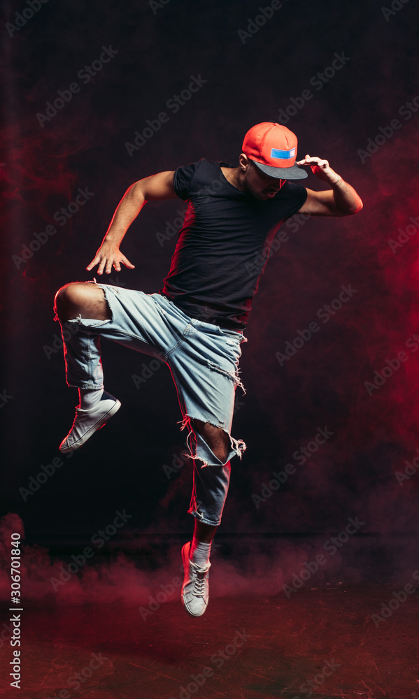 young caucasian man jumping in the air isolated over smoky background, street dance, hip-hop concept