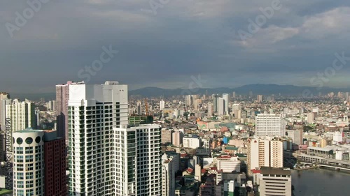 Side overview of the cityscape and skylines with a background of silhouette mountains under the dark cloudy sky photo