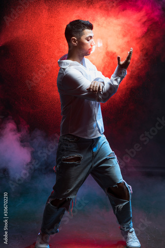 red smoke in the background, young caucasian man wearing t-shirt and jeans show various steps of dance, process of dancing in studio