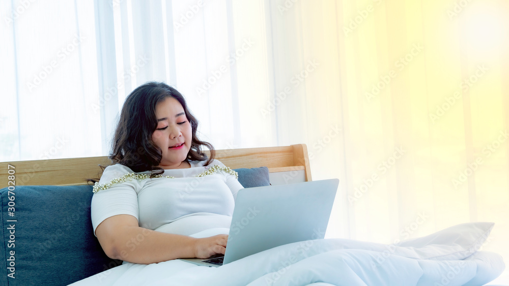 Fat women using laptop computer in the bedroom Fat women using laptop computer in the bedroom
