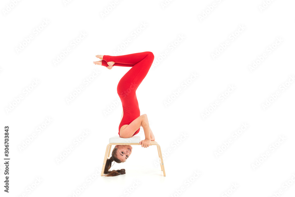 European brunette girl in a red tracksuit wishes gymnastic exercises upside down on a white background European brunette girl in a red tracksuit wishes gymnastic exercises upside down on a white background