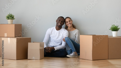 Happy smiling young mixed race family couple sitting on floor.