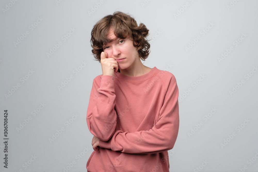 Caucasian mature woman with curly hair in pink pulover thinking about her life problems being sad and confused. Studio shot Caucasian mature woman with curly hair in pink pulover thinking about her life problems being sad and confused. Studio shot